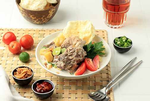 Soto Betawi Iga, Traditional Beef Ribs Soup from Betawi, Jakarta. Indonesia Traditional Soup made from Cow and Coconut Milk, Contain of Potato, Tomato, and Served with Emping Melinjo