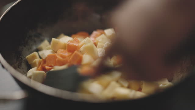 mixing root vegetable cubes with olive oil in frying pan