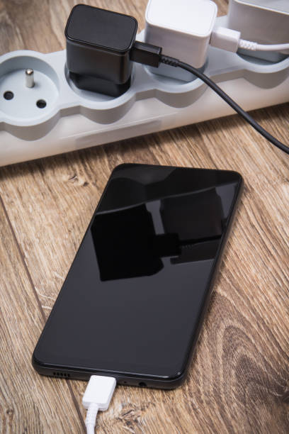 istock Black smartphone and chargers connected to electrical power strip. Various devices charging concept 1476455803