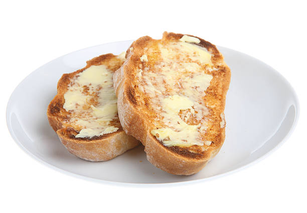 Two slices of buttered toast on a white plate Thick hand-cut slices of a traditional bloomer loaf toasted and buttered Slice of Toast with Butter stock pictures, royalty-free photos & images