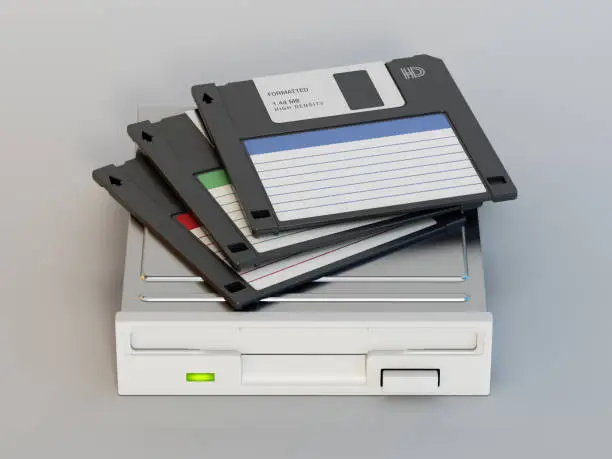 Photo of Generic HD floppy disks standing on floppy disk drive. Retro computer and data archive technology concept