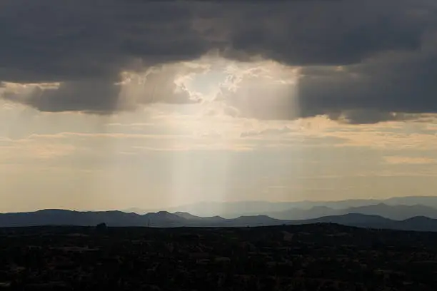 Shaft of sunlight through rainclouds in Santa Fe, New Mexico.  Jemez Mountains in the background.  Wide angle lens  - See lightbox for more