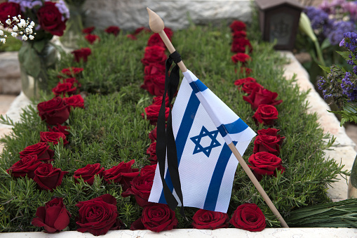 A flag of the State of Israel rests on a grave of a fallen soldier covered with colorful flowers in the Har Herzl military cemetary in Jerusalem on Memorial Day in Israel.