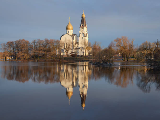 Orthodox Church is reflected in lake water: spring, sun morning light, May.