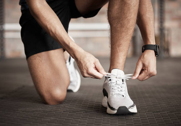 istock Fitness, man and shoe lace tie getting ready for running exercise, workout or training at gym. Sporty male, person or guy shoes in preparation for sport run, cardio or warm up on floor at gymnasium 1476493263