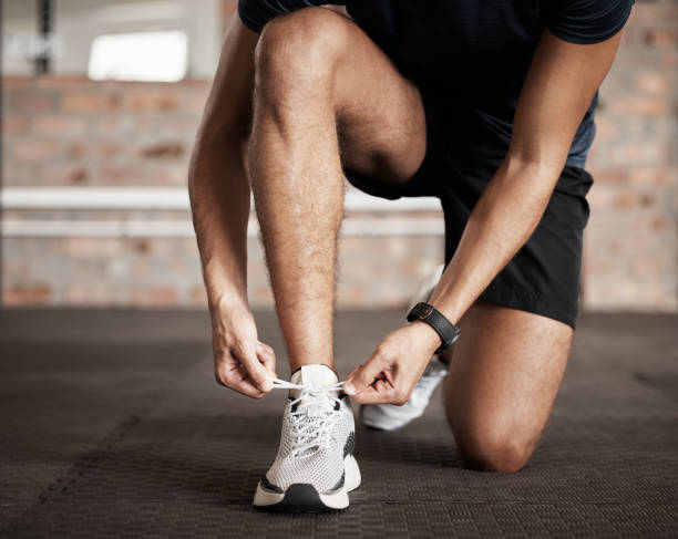 istock Fitness, man and tying shoe lace getting ready for running exercise, workout or training at gym. Sporty male, person or guy shoes in preparation for sport run, cardio or warm up on floor at gymnasium 1476493266