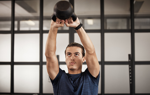 Man, kettlebell and gym fitness of a person training with focus mindset in a health studio. Power train, weight workout and wellness target goal of an athlete doing cardio and arm challenge breathing