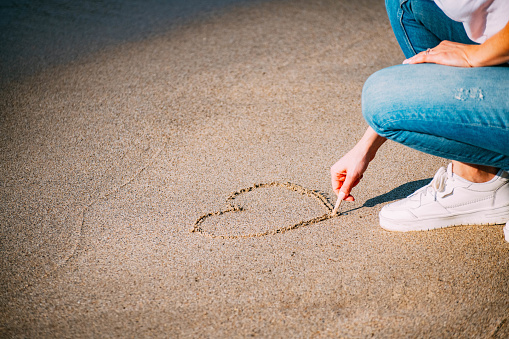 Woman Drawing Heart on Sand at Beach