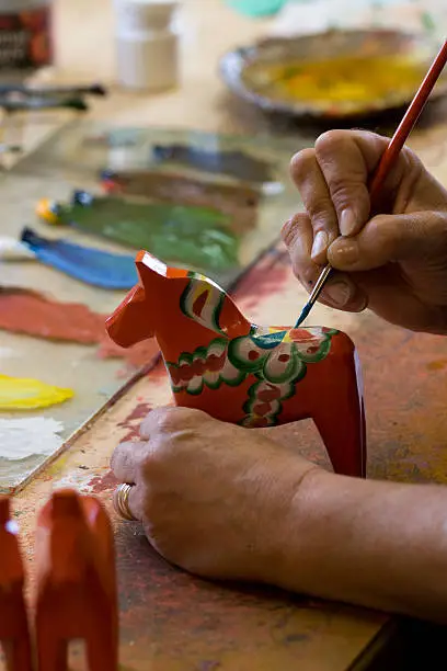 A Dalarna horse is being hand painted with the traditional colors.