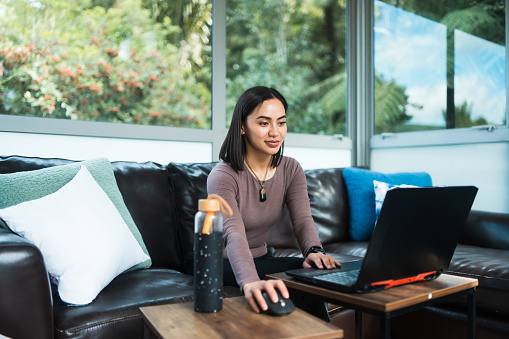 Young Maori woman working from home using laptop in  Auckland, New Zealand.