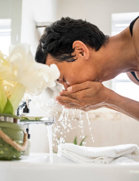 istock Person washing their face in bathroom sink 1476508957