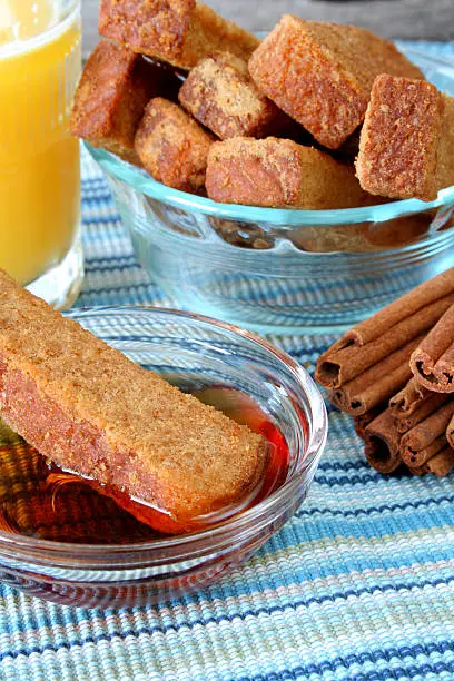 close up of a piece of French toast stick in a bowl of syrup.