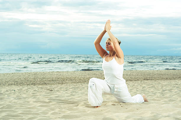 Young cute girl training on the beach. stock photo