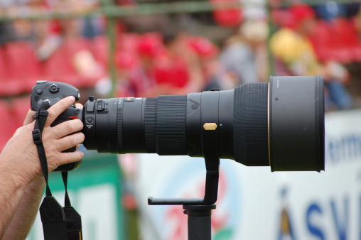 Sport photographer using long zoom lense to capture one of the hungarian football game.