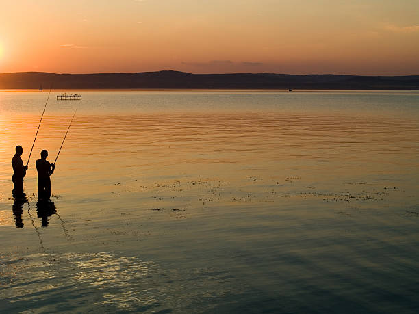 Two fishermen by sunset in lake Balaton (Hungary).