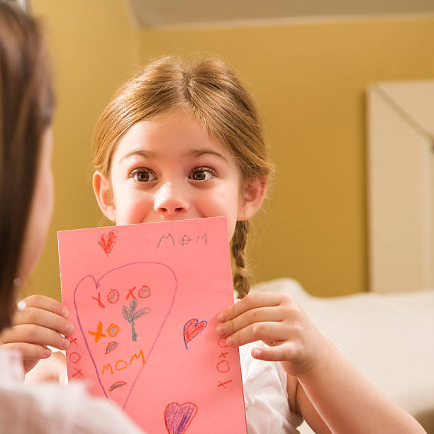 Girl giving Mom a drawing. stock photo