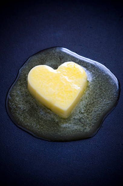 butter heart melting a heart shaped butter pat melting on a non-stick surface saturated fat stock pictures, royalty-free photos & images