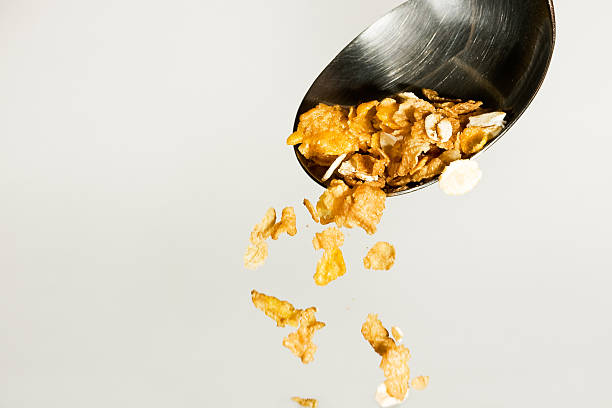 Cereals poured from a table spoon on grey background stock photo