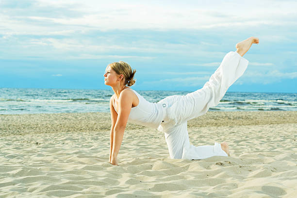 Young cute girl training on the beach. stock photo