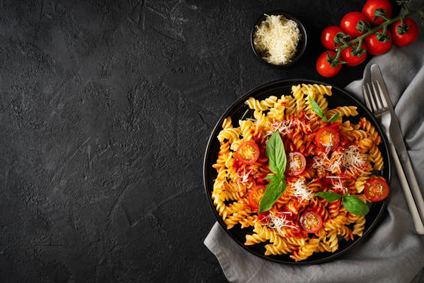 istock Fusilli pasta with tomatoes, basil, parmesan, and sauce on back background 1476567937