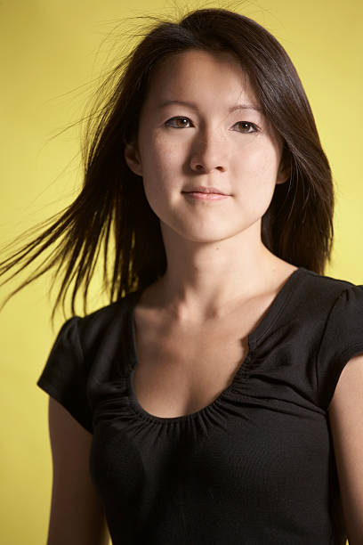 Portrait of young Asian woman against yellow stock photo