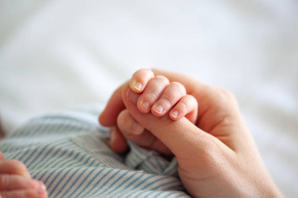 main de mères de fixation de chéri de garçon - baby newborn human hand mother photos et images de collection