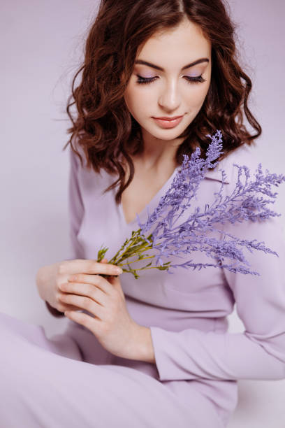 istock Attractive woman with bouquet on lilac background 1476571519