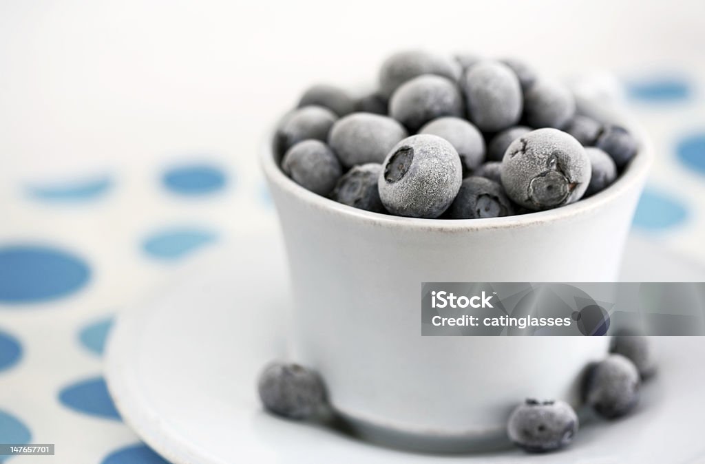 Summer dessert, frozen blueberries Frozen blueberries in the cup with saucer, shallow depth of field Blueberry Stock Photo