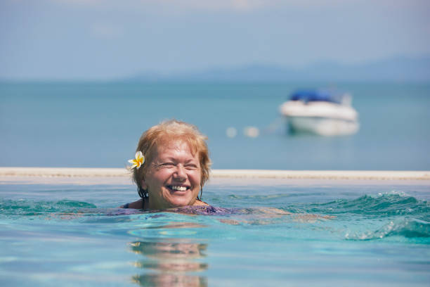 istock Active laughing senior woman is swimming in pool 1476580464
