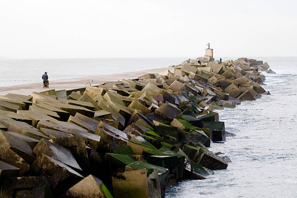 Los pescadores y las personas que salen a caminar en el breakwater - foto de stock