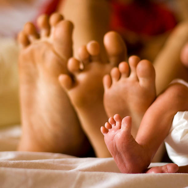 Father, mother, child, and newborn bare feet stock photo