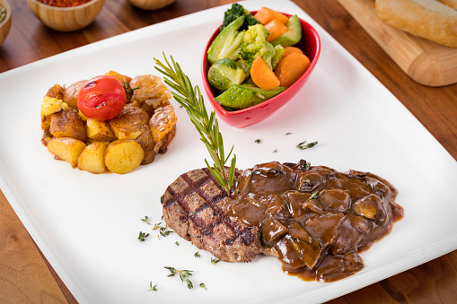 Flat lay of grilled steak served with frird vegetables and garlic sauce