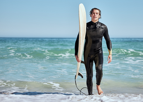 Portrait, man and surfer on beach, training and wet for competition, relax and summer break. Male, athlete and guy with surfboard, water or fun for fitness, practice or workout for wellness or health