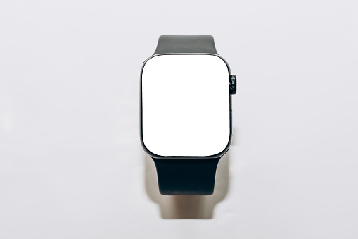 A black technological smart watch lies on a wooden background with a white screen for text space
