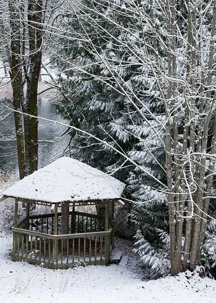 A waterfront gazebo is covered with fresh, powdery snow.