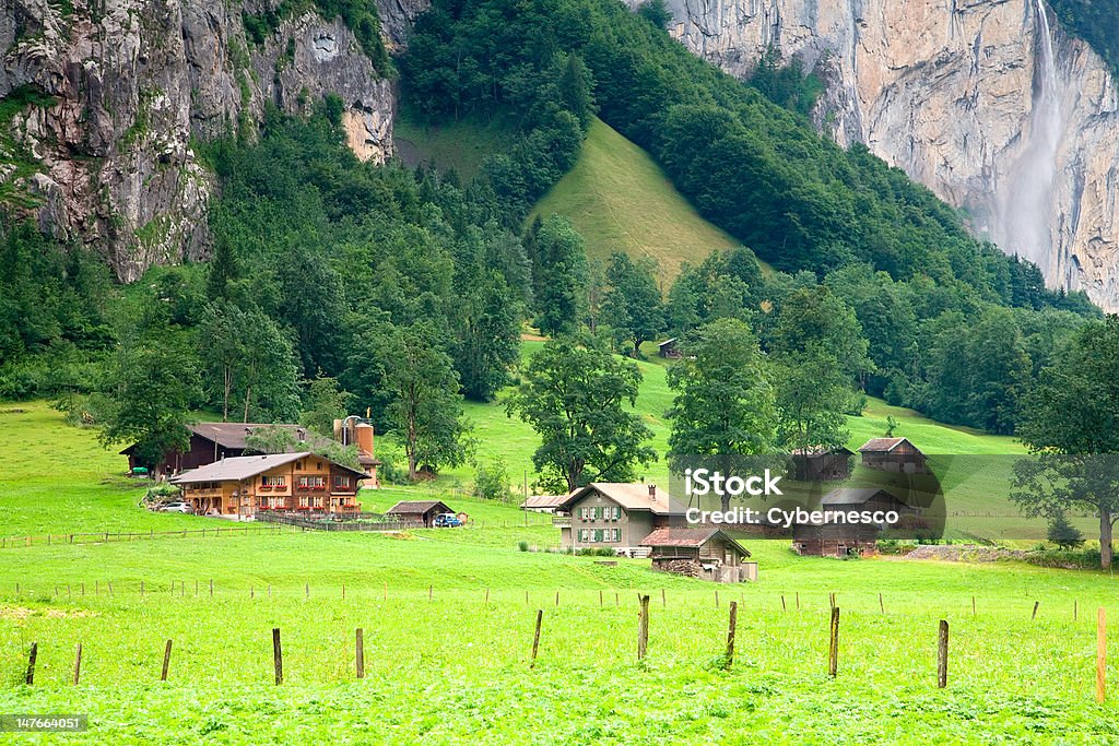 Residências perto de uma íngreme montanha rochosa na Suíça. - Foto de stock de Cabana de Madeira royalty-free