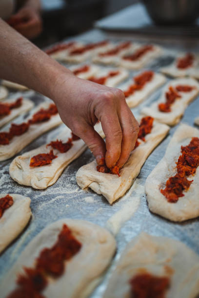 istock Baker putting chorizo meat on bread dough 1476642159