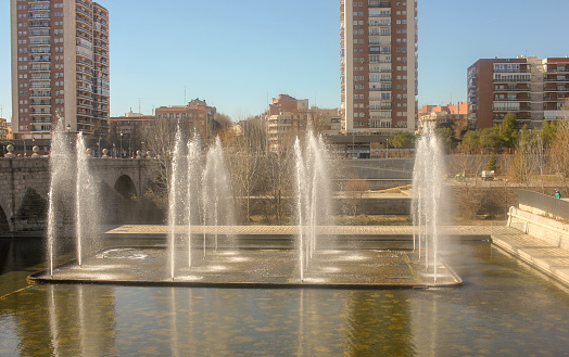 fountains in river Manzanares in Madrid with some high buildings in the background