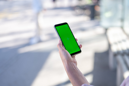 Person holding smartphone with chroma key green screen in hand close up