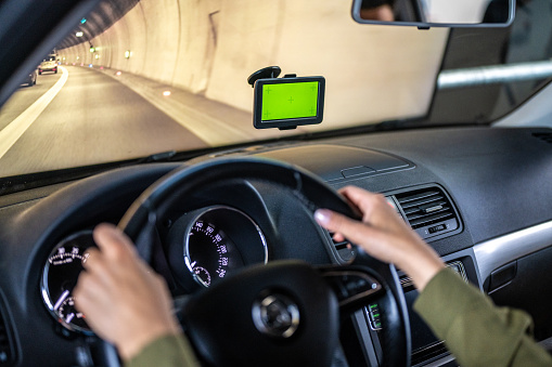Female driver using GPS navigator with green screen while driving car in tunnel