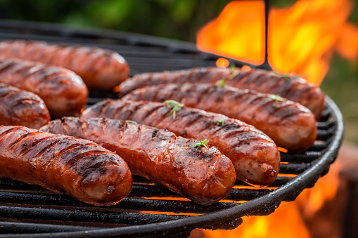 Hot sausage with spices on grill with fire in summer in garden