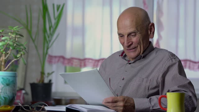 Elderly man reads printed article and enjoys end of work