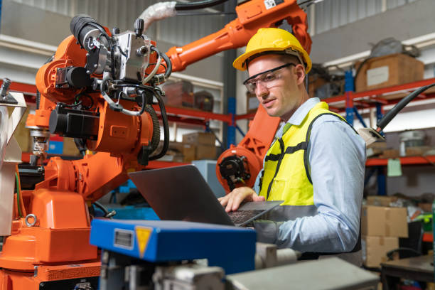 istock Male automation engineer testing new robot arm welding machine by using laptop control for operating at industrial factory 1476665904