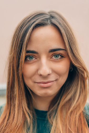 close up portrait of natural beauty caucasian young woman with long light brown hair and green eyes hinting at a sly smile