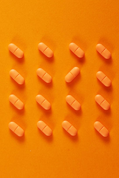 istock Pills in a row on orange background 1476681092