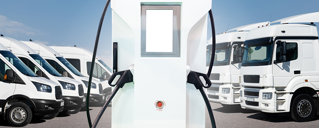 Electric vehicles charging station on a background of trucks and vans. Green fleet concept