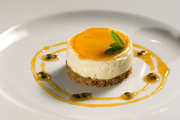 Lemon cheesecake with biscuit crumb base and passionfruit jus sauce with mint leaf decoration (created by Gavin Meiklejohn, the Cobbles Inn, Kelso, Scotland - may be used by restaurants in other areas).