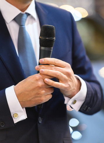 Midsection of unrecognizable businessman making a statement, holding microphone