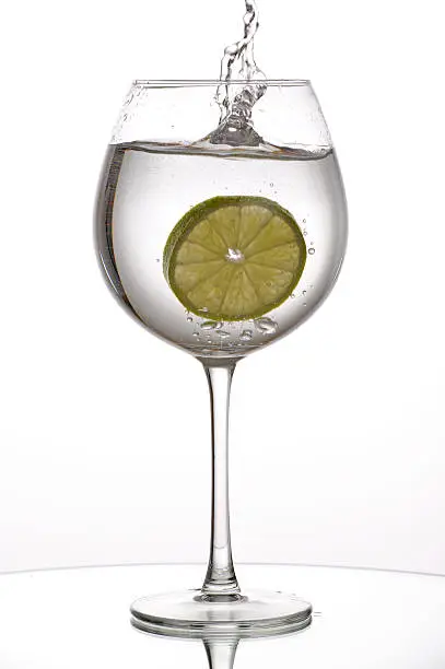 Photo of Slice of lime splashing into wine glass