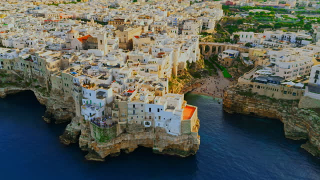 Aerial view of Polignano a Mare on rocky cliff by sea.